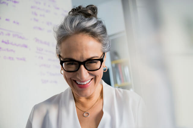 A middle-aged professional woman smiling and wearing glasses.