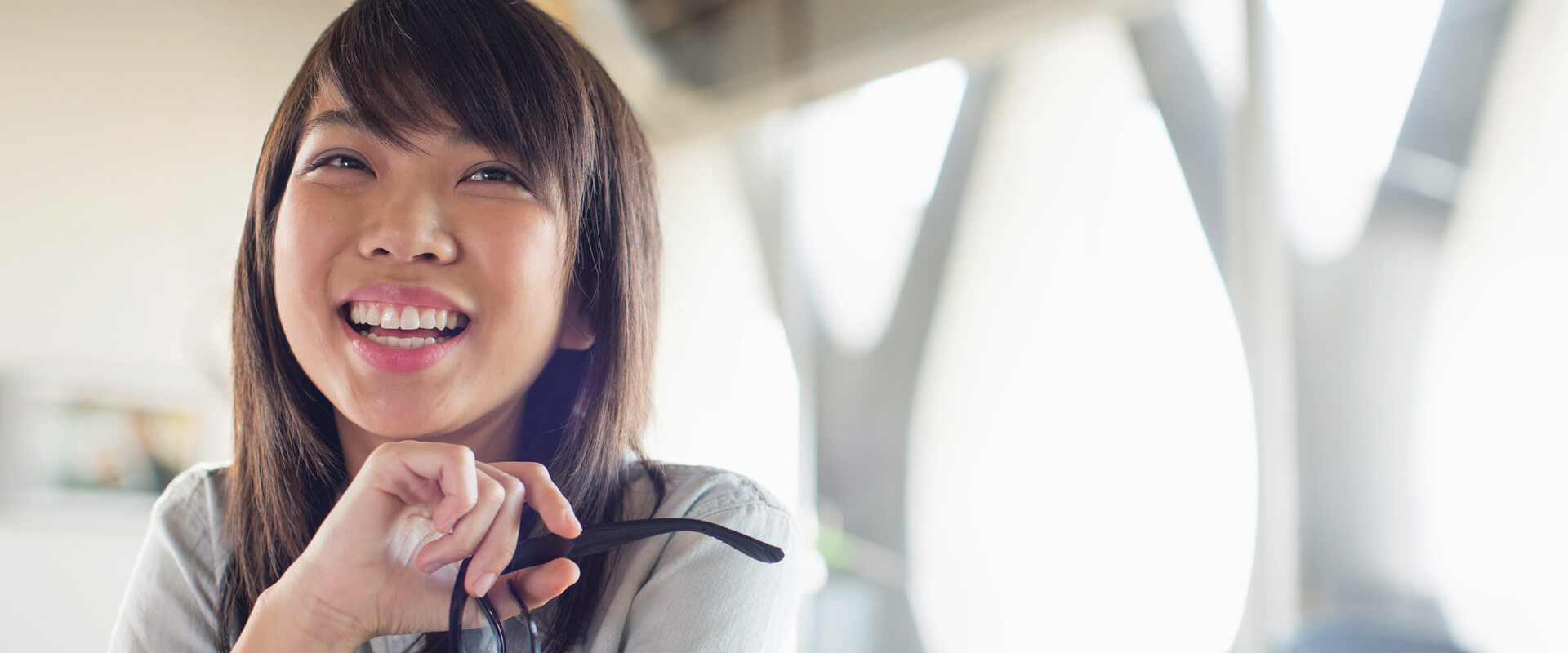 Young woman smiling and holding glasses.