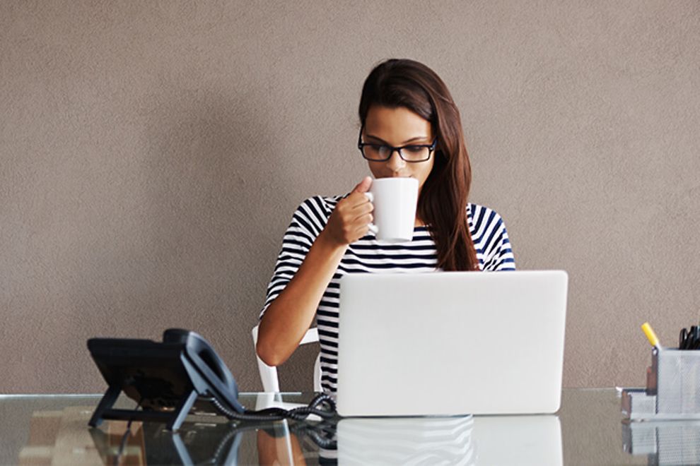 Young professional woman sips coffee at her desk