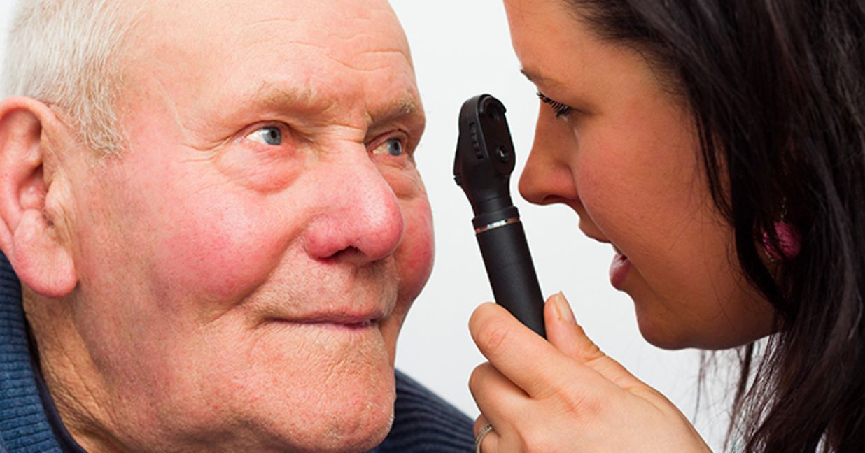 An eye doctor examining an older man's eye