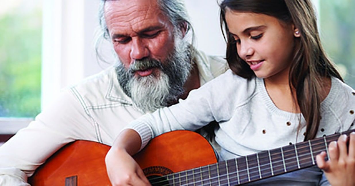 bearded father with daughter playing acoustic guitar 